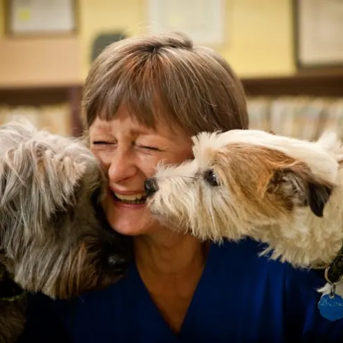 Woman smiling in between two dogs.